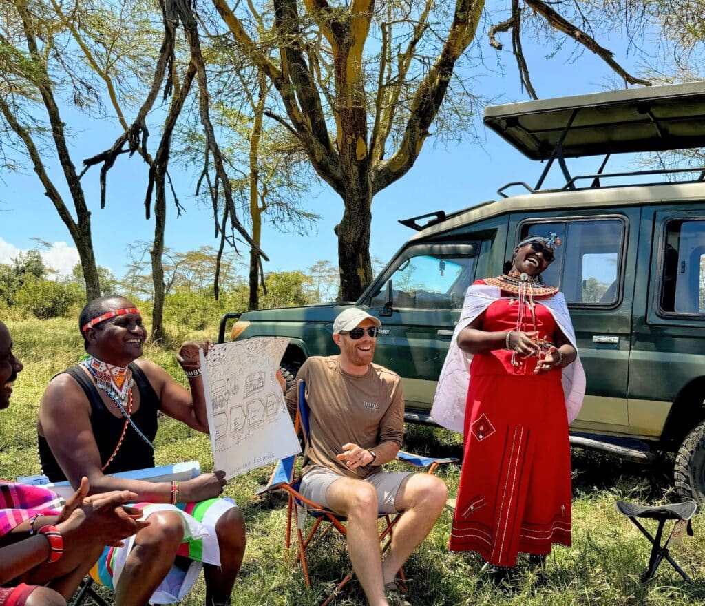 Samburu facilitators presenting alongside participants at a workshop under acacia trees in northern Kenya
